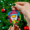 Colorful gnome ornament held by a hand with green nail polish against a Christmas tree background.