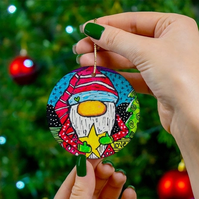 Colorful gnome ornament held by a hand with green nail polish against a Christmas tree background.