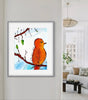 Framed artwork of an orange bird on a branch in a living room setting