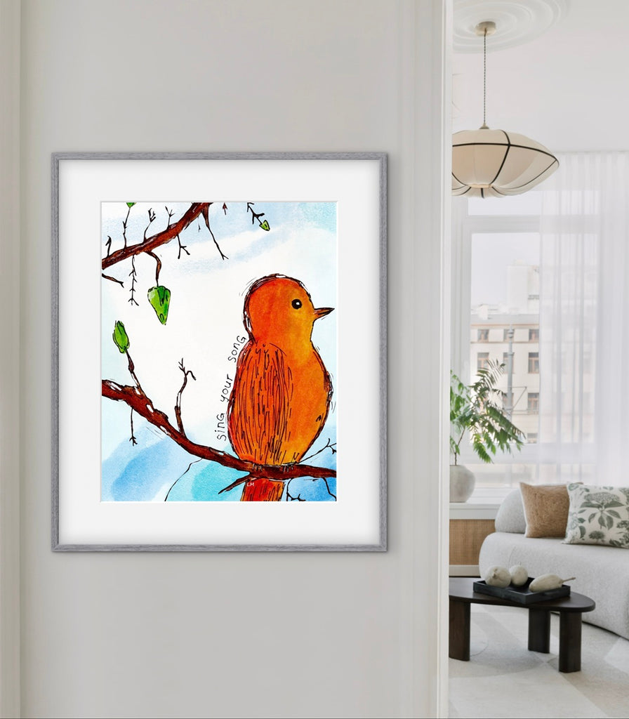 Framed artwork of an orange bird on a branch in a living room setting
