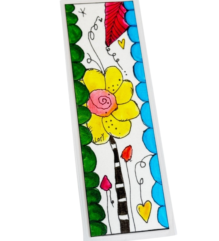 A colorful hand-drawn style art bookmark featuring a large yellow flower with a pink center, green leaves, blue scalloped borders, and small hearts on a white background. Signed by 'Lori', the artist