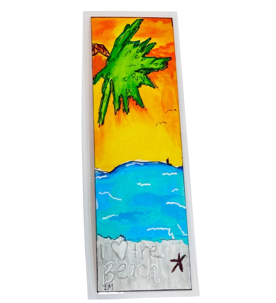 beach scene painted on a laminated bookmark with a sunset sky and a palm tree, Initials for the artist 'LM' on lower corner and 'I heart the beach' text in the sand next to a starfish