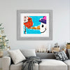 Framed artwork of a snowman and cardinal on a wall above a sofa with Christmas decorations.