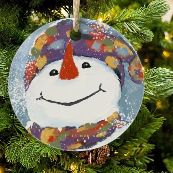 Snowman ornament with colorful hat hanging on a Christmas tree.