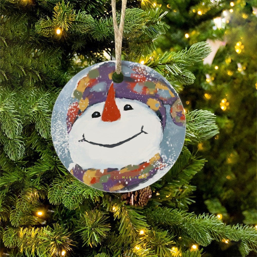 Artisan snowman ornament on a Christmas tree with lights.