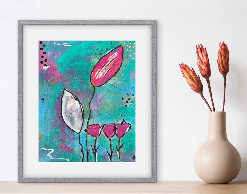 Framed abstract floral artwork on a wall next to a vase with dried flowers.
