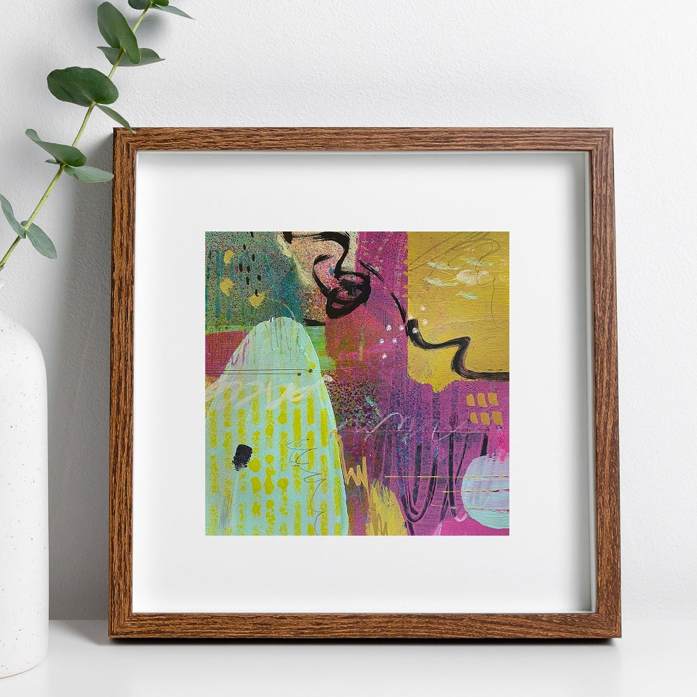 Framed abstract artwork with a colorful design on a white wall.