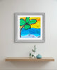 Framed artwork of a palm tree and beach scene on a wall above a shelf with decorative items.