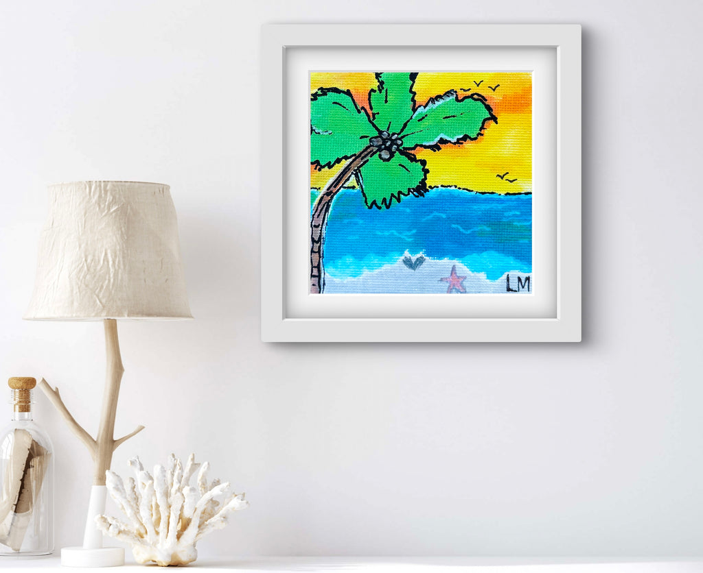 Framed artwork of a tropical scene with a palm tree, beach, and sea on a white wall.