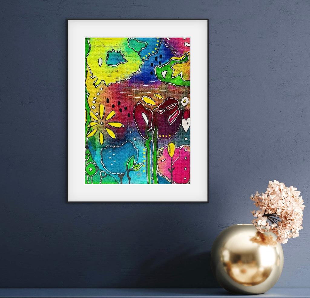 Framed colorful abstract art piece on a dark blue wall with a decorative vase.