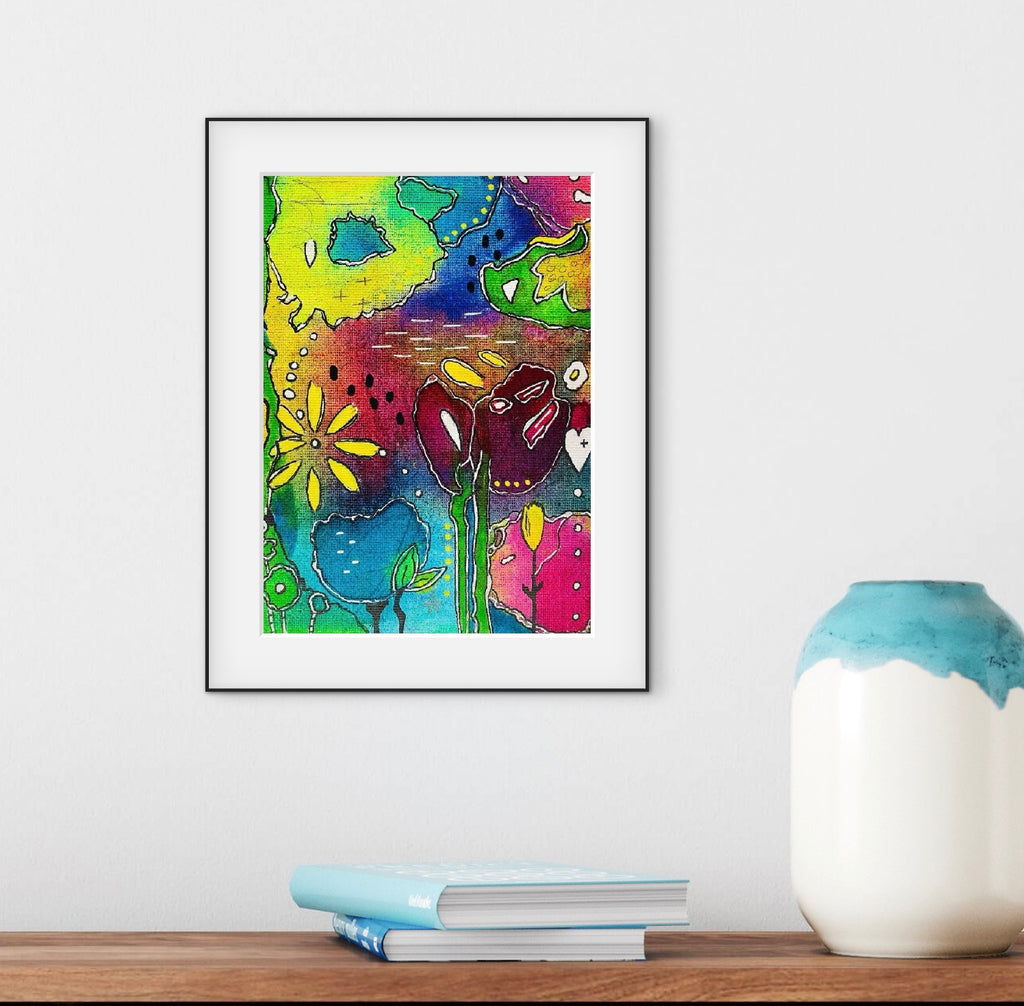Colorful abstract art print on a white wall above a wooden shelf with books and a vase.
