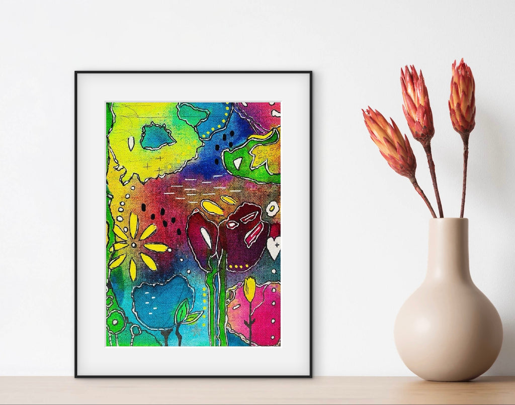 Colorful abstract art print on a wall next to a vase with dried flowers.