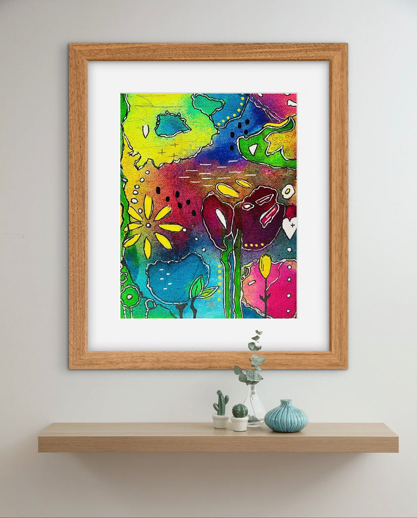 Framed colorful abstract painting on a wall above a shelf with decorative items.