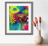 Framed colorful floral artwork on a white wall with a vase of dried flowers.