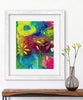 Colorful abstract painting in a white frame on a wall next to a vase with flowers.