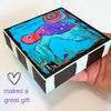 a hand holding a wood block with a turtle painting on it. The text in photo says 'makes a great gift'