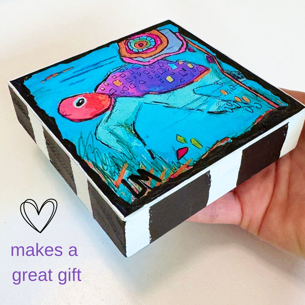 a hand holding a wood block with a turtle painting on it. The text in photo says 'makes a great gift'