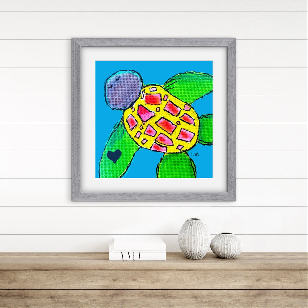 Framed artwork of a colorful turtle on a wooden surface with a white wall background