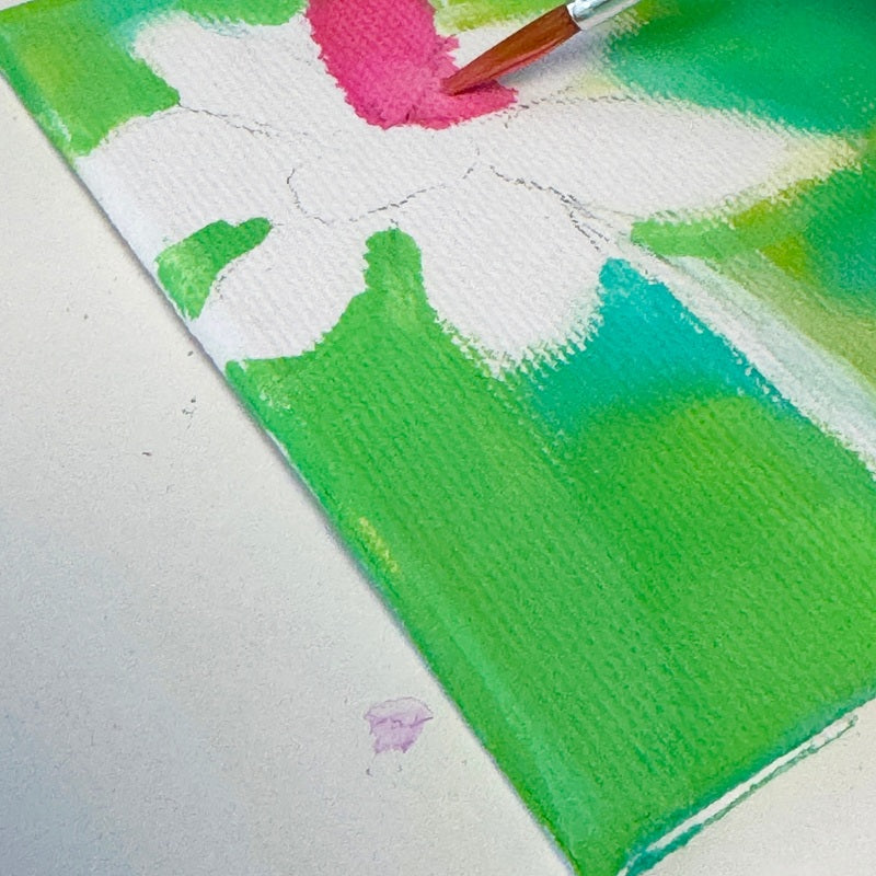 Artistic creating a flower with green, white, and pink colors on a textured surface.
